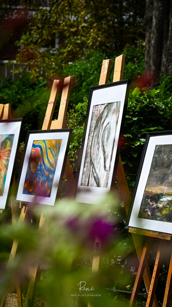 Fotowerk tentoongesteld op houten schildersezels tijdens een buitenexpositie