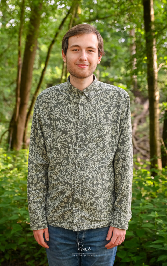 Jonge man in een groen overhemd tijdens een portretshoot in het bos