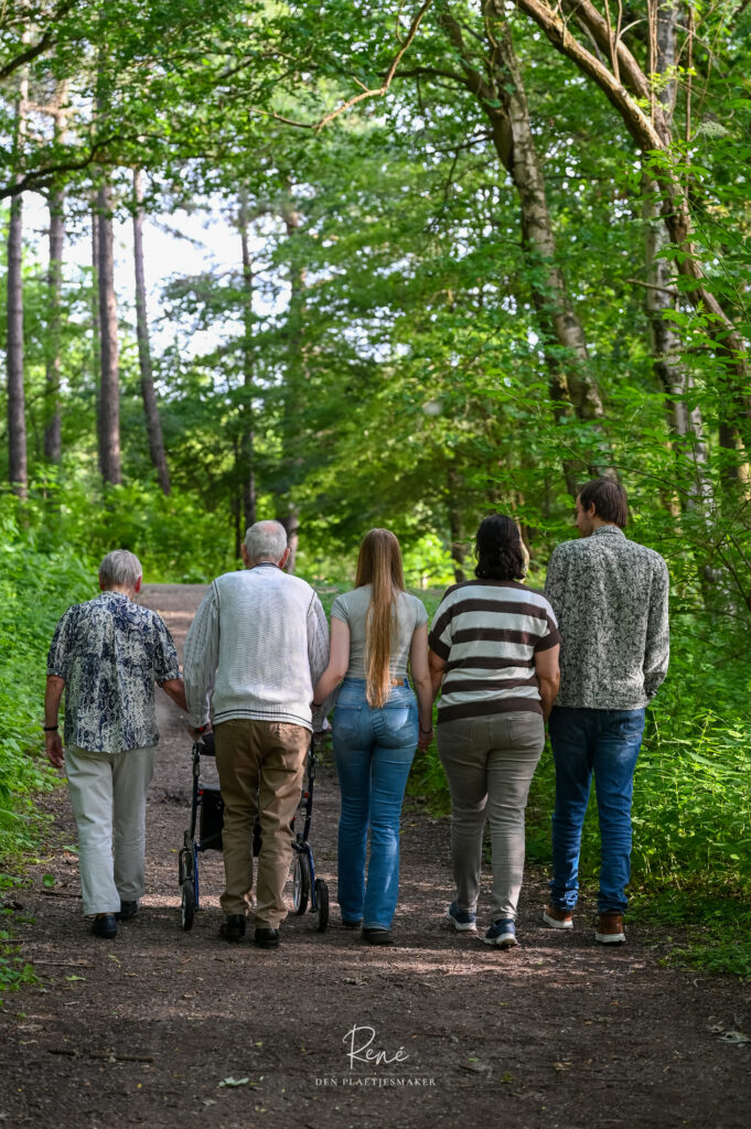 Familie van drie generaties loopt samen door het bos tijdens een fotoshoot